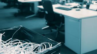 Papier déchiqueté dans une poubelle avec un espace ouvert flou et un bureau moderne en arrière-plan 